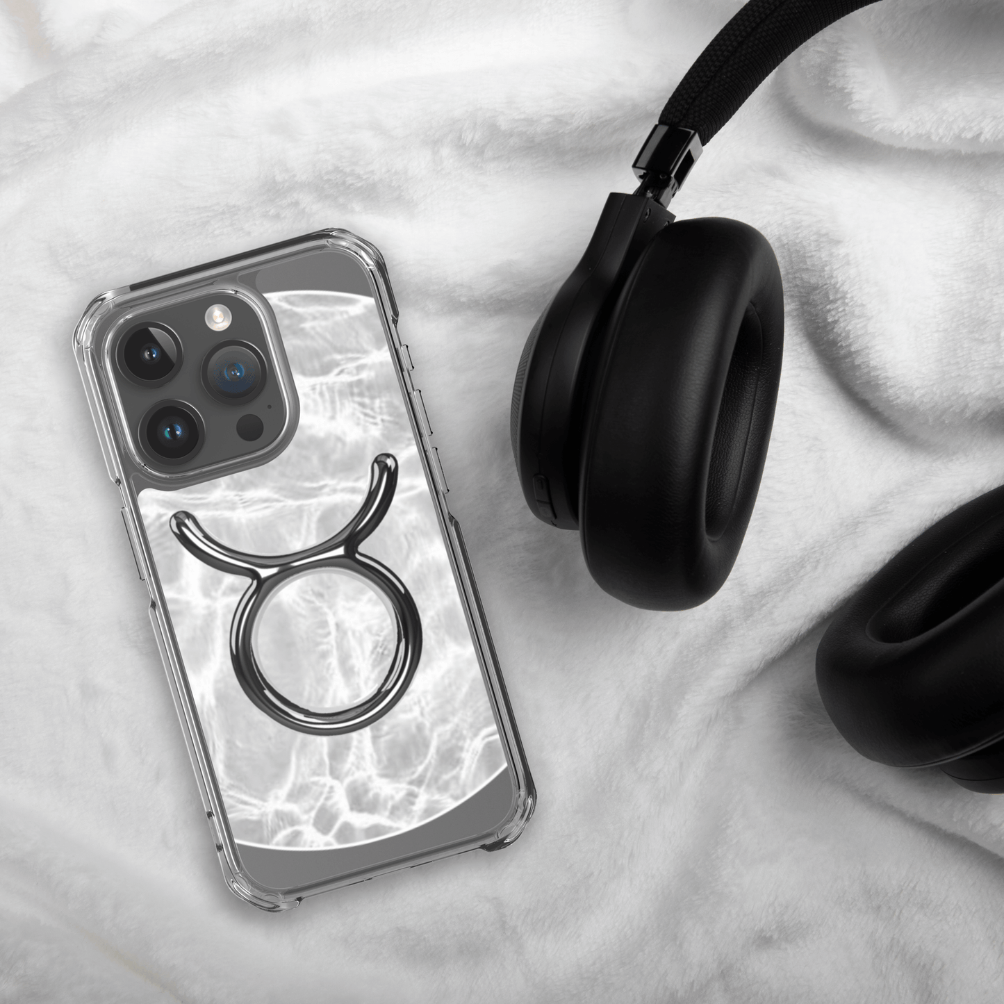 Zodiac Taurus MagSafe clear iPhone case with metallic design on marble background next to headphones.