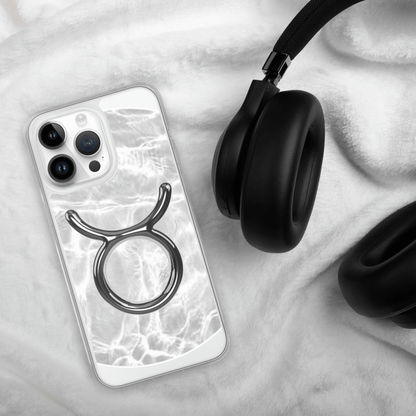 Zodiac Taurus Magsafe clear iPhone case with metallic design, placed next to black headphones on a soft surface.