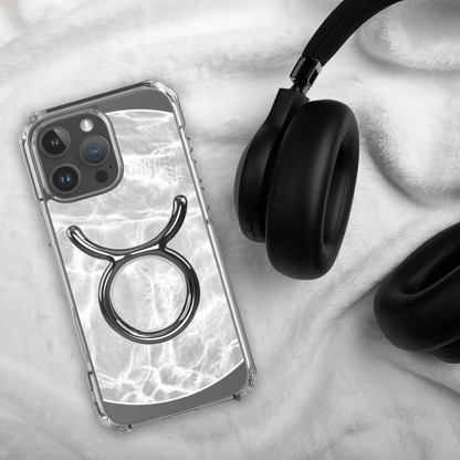 Zodiac Taurus Magsafe clear iPhone case with marble design, laid beside black headphones on soft fabric surface.