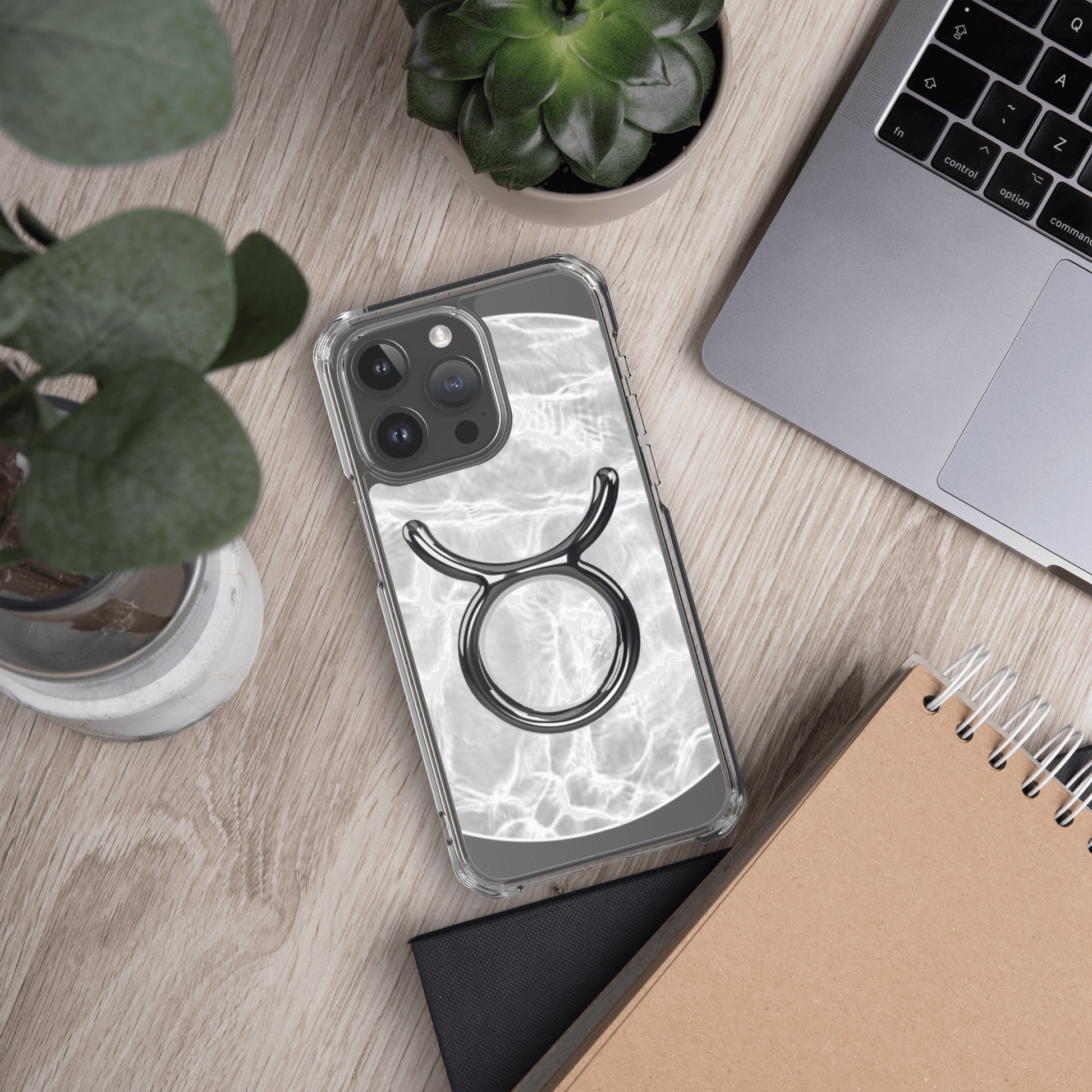 Zodiac Taurus Magsafe clear iPhone case with marble metallic design on a wooden desk.