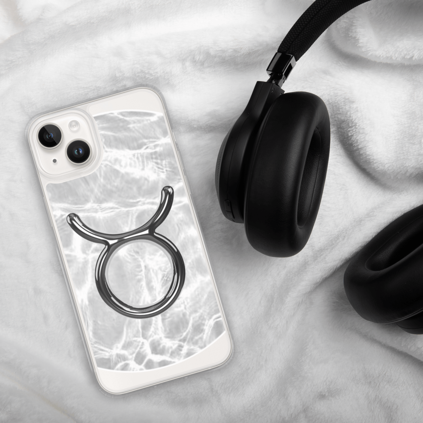 Zodiac Taurus Magsafe Clear iPhone Case in marble metallic design beside black headphones