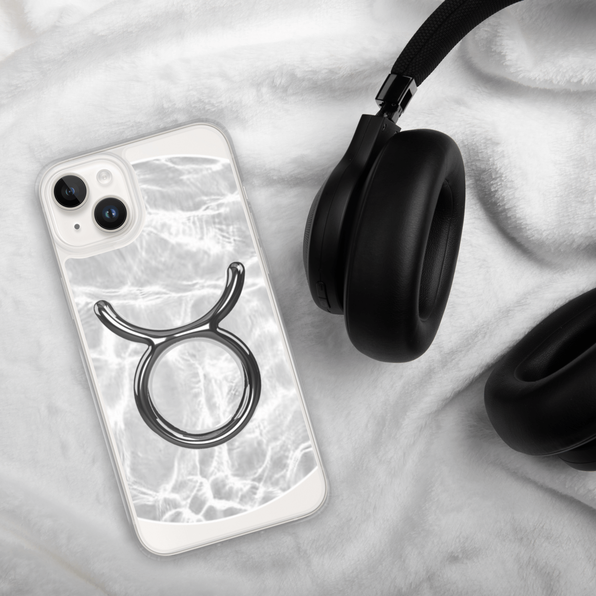 Zodiac Taurus Magsafe Clear iPhone Case in marble metallic design beside black headphones
